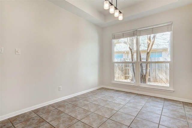 spare room featuring light tile patterned flooring, a raised ceiling, and baseboards