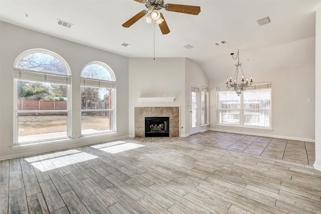 unfurnished living room with ceiling fan with notable chandelier, a tiled fireplace, visible vents, and wood tiled floor