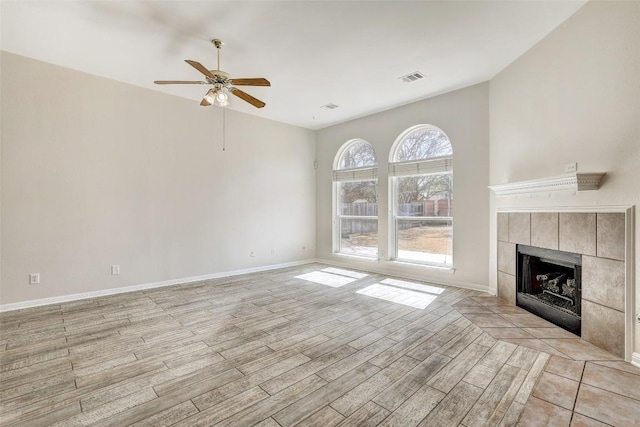 unfurnished living room with a fireplace, light wood finished floors, visible vents, ceiling fan, and baseboards