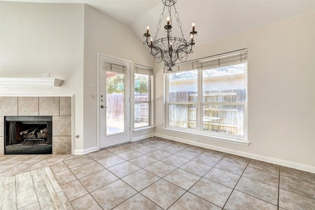 unfurnished dining area with a tile fireplace, a notable chandelier, vaulted ceiling, and baseboards