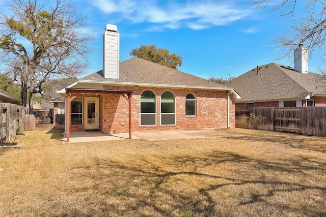 rear view of property featuring a patio area, a lawn, a fenced backyard, and brick siding