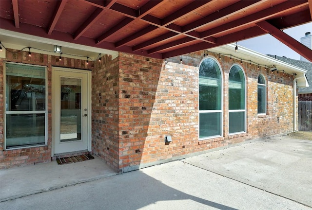 property entrance featuring a patio area and brick siding