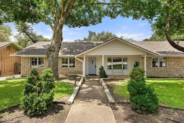 ranch-style house with stone siding, a shingled roof, and a front lawn