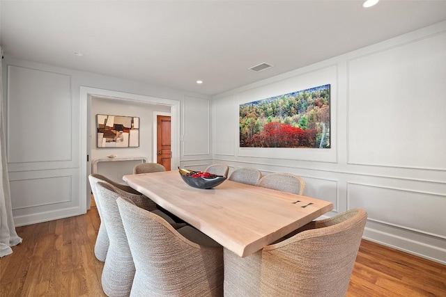 dining space with light wood-type flooring, visible vents, a decorative wall, and recessed lighting