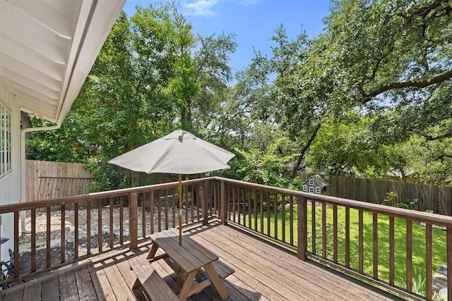 wooden terrace featuring a fenced backyard, an outbuilding, and a yard