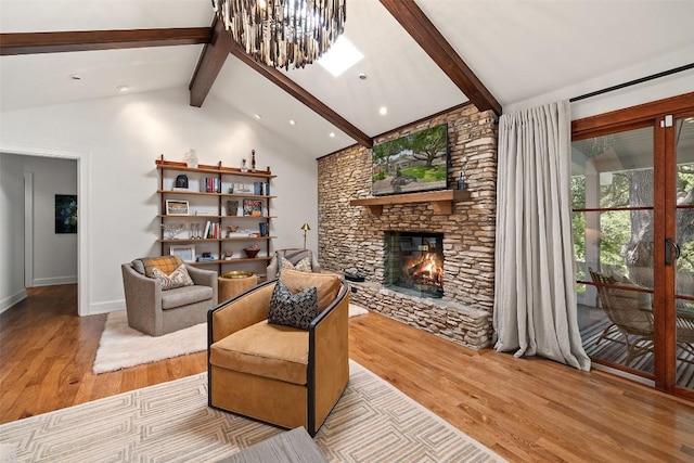 living area featuring beam ceiling, an inviting chandelier, a stone fireplace, wood finished floors, and baseboards