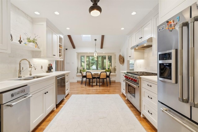 kitchen featuring stainless steel appliances, white cabinetry, and under cabinet range hood