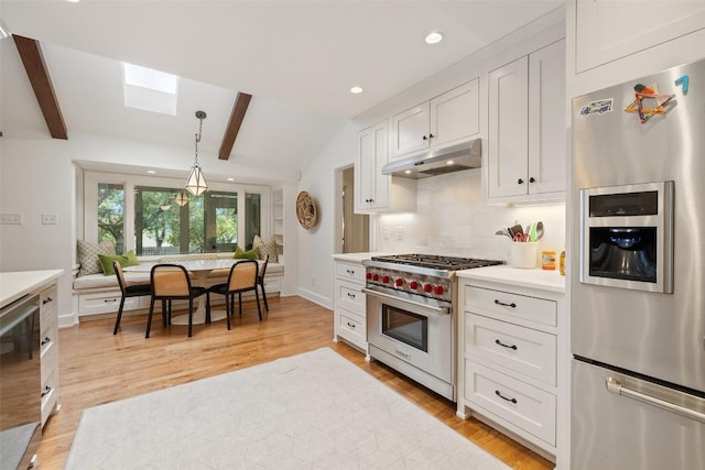 kitchen with tasteful backsplash, vaulted ceiling with skylight, stainless steel appliances, light countertops, and under cabinet range hood