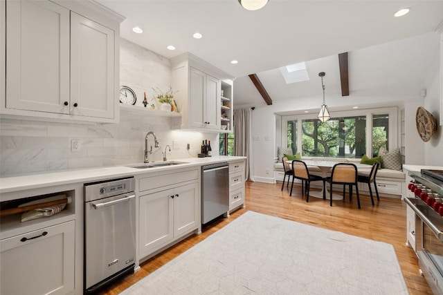 kitchen featuring open shelves, light countertops, decorative backsplash, appliances with stainless steel finishes, and a sink