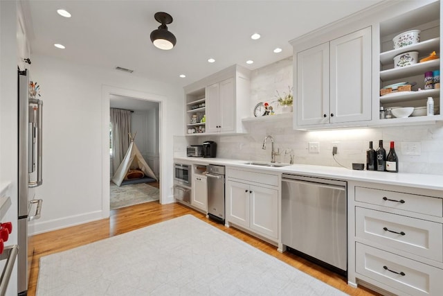 kitchen featuring open shelves, visible vents, appliances with stainless steel finishes, light wood-style floors, and a sink