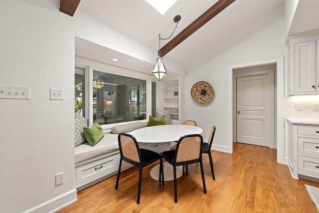 dining area featuring light wood finished floors, lofted ceiling with skylight, breakfast area, and baseboards