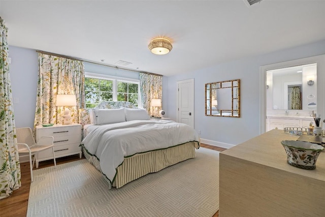 bedroom featuring light wood-type flooring, ensuite bath, and baseboards