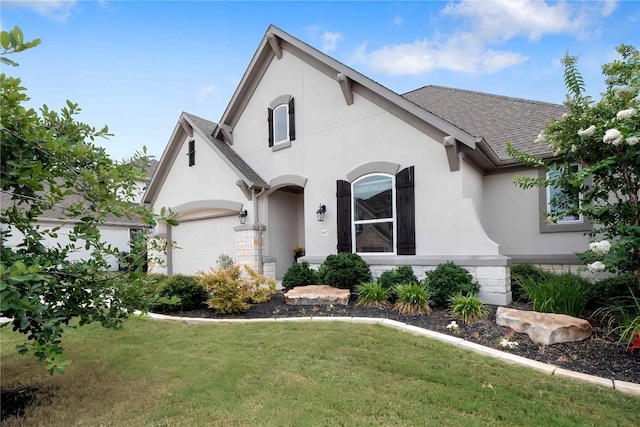 view of front of house with a garage, roof with shingles, a front yard, and stucco siding