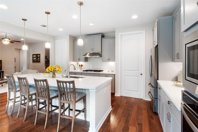 kitchen with gray cabinets, visible vents, appliances with stainless steel finishes, a sink, and under cabinet range hood