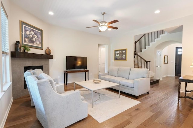 living area featuring stairs, recessed lighting, a fireplace, and wood finished floors