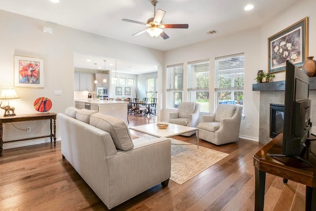 living area with recessed lighting, visible vents, baseboards, and wood finished floors