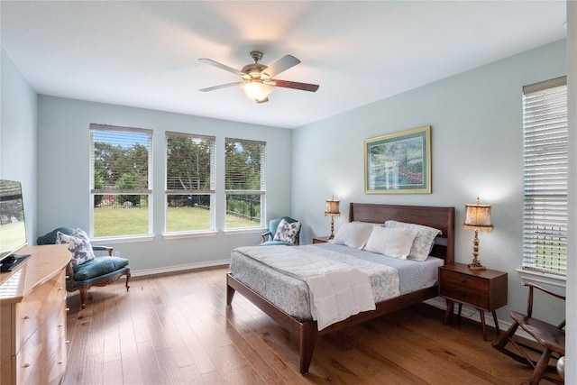 bedroom featuring a ceiling fan, baseboards, and wood finished floors