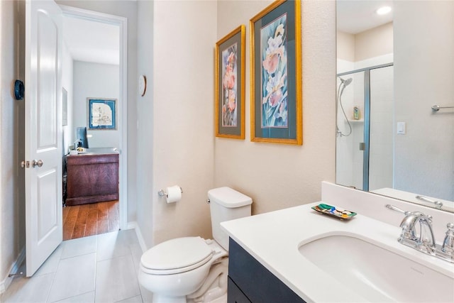 full bath with toilet, a shower with shower door, vanity, tile patterned flooring, and baseboards