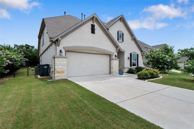 french country style house with a garage, a front yard, fence, and stucco siding