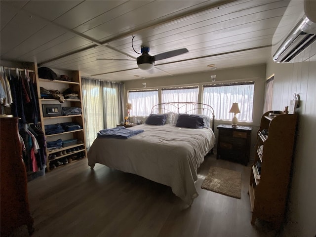 bedroom with wooden ceiling, a wall unit AC, ceiling fan, and wood finished floors