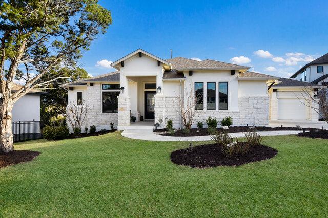 prairie-style house featuring stone siding, fence, stucco siding, and a front yard