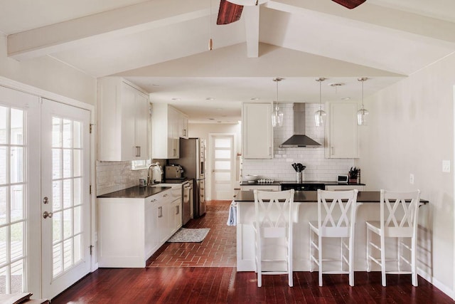 kitchen with a breakfast bar, white cabinetry, french doors, wall chimney range hood, and dark countertops