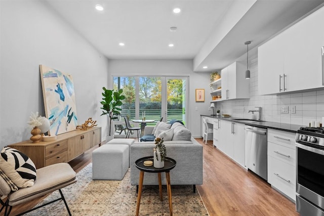 living area featuring light wood-type flooring, baseboards, and recessed lighting