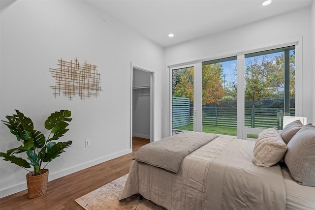 bedroom featuring a spacious closet, recessed lighting, wood finished floors, and baseboards