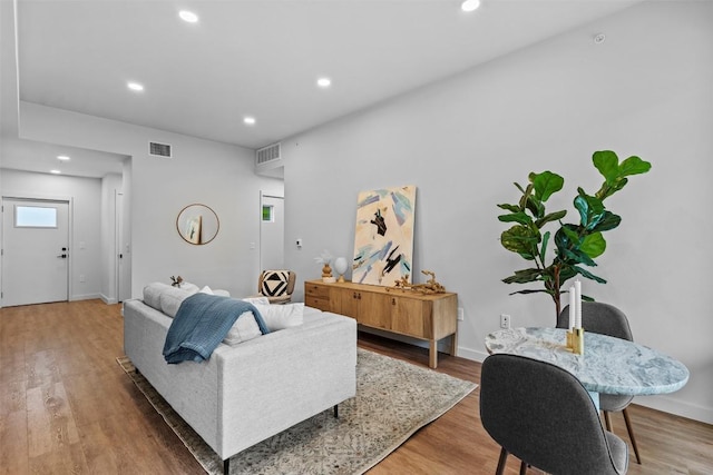 living room featuring baseboards, light wood finished floors, visible vents, and recessed lighting