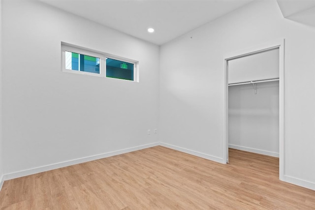 unfurnished bedroom with recessed lighting, baseboards, a spacious closet, a closet, and light wood finished floors