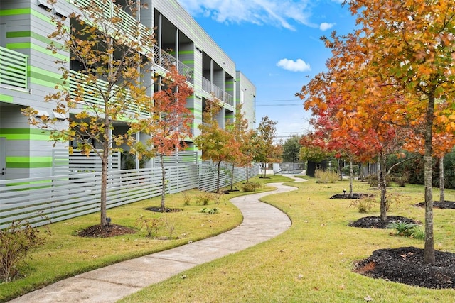 view of community featuring a lawn and fence