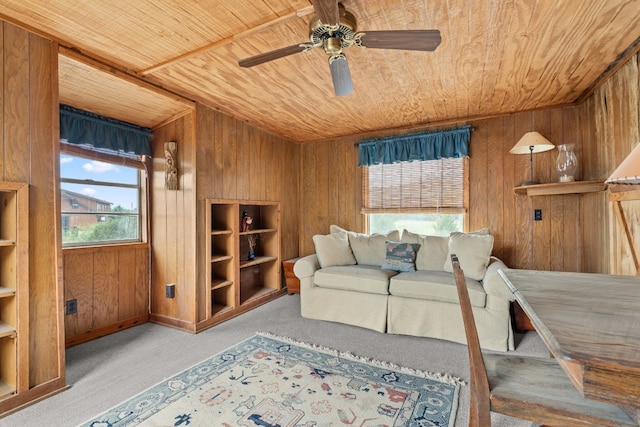 living area featuring wooden ceiling, a ceiling fan, carpet flooring, and wood walls