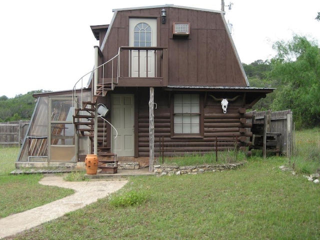 view of front facade with log exterior, stairway, a front yard, and fence