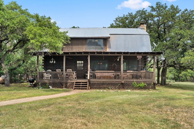 view of front of house featuring metal roof, covered porch, log siding, a front lawn, and a chimney