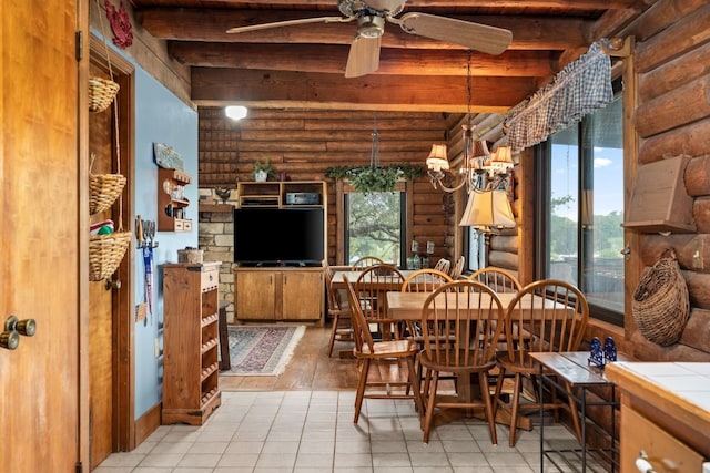 dining area featuring beam ceiling, light tile patterned floors, rustic walls, and ceiling fan with notable chandelier