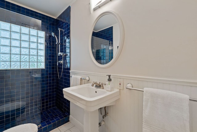 bathroom with tile patterned floors, wainscoting, and tiled shower