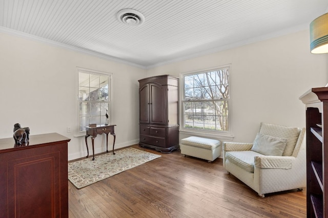 living area with baseboards, visible vents, wood finished floors, and ornamental molding