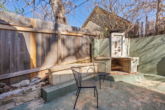 view of patio with a fenced backyard and an outdoor fireplace