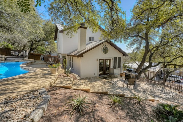 rear view of property featuring a fenced in pool, french doors, stucco siding, a patio area, and a fenced backyard