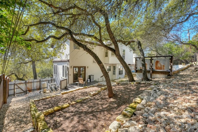 rear view of house with a deck, french doors, a fenced backyard, and stucco siding