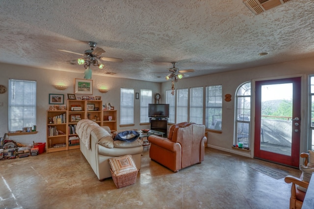 living area with ceiling fan, visible vents, and a textured ceiling