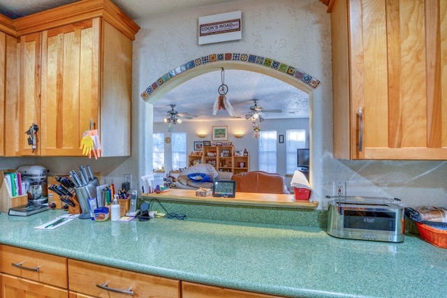 kitchen with arched walkways, light countertops, and a ceiling fan