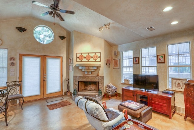 living area with baseboards, visible vents, a fireplace with raised hearth, a textured wall, and french doors