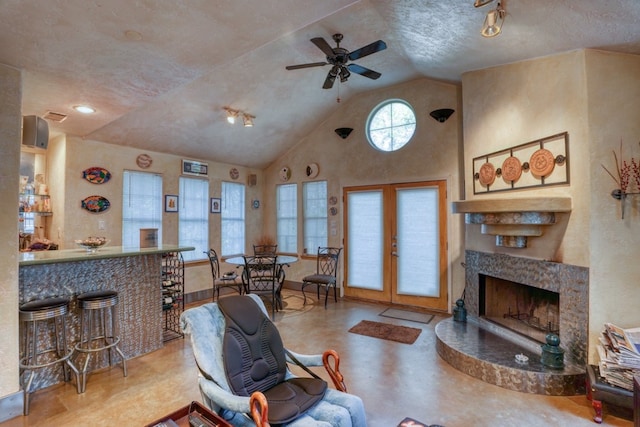 living room with baseboards, a fireplace with raised hearth, ceiling fan, french doors, and high vaulted ceiling