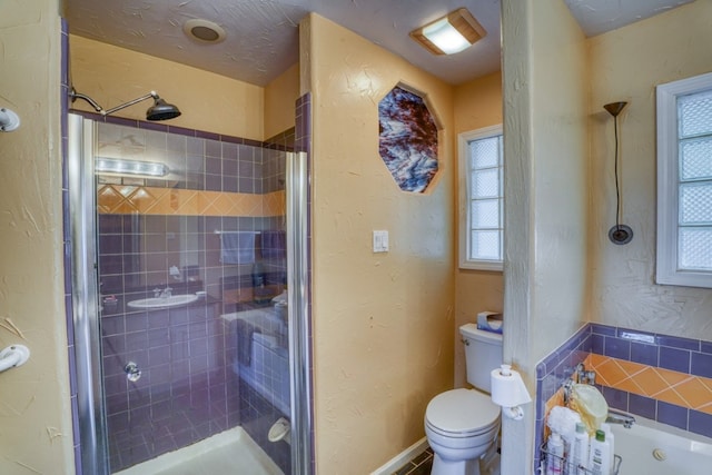 full bath with a stall shower, a textured wall, toilet, and a bath