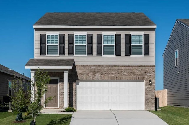 view of front of property with driveway, a front yard, a garage, and brick siding