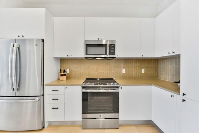 kitchen featuring white cabinetry, decorative backsplash, stainless steel appliances, and light countertops