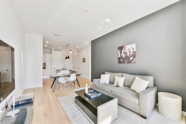 living room featuring light wood-type flooring, visible vents, and recessed lighting