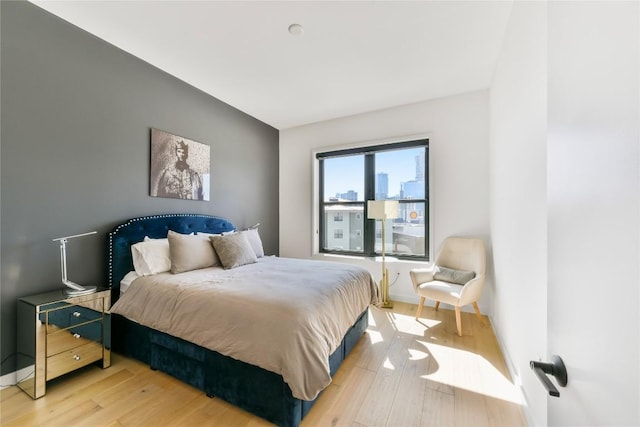 bedroom featuring a view of city, baseboards, and wood finished floors