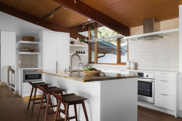 1400 Mount Larson Rd, Austin, TX 78746 - kitchen featuring open shelves, appliances with stainless steel finishes, wooden ceiling, track lighting, and wall chimney exhaust hood